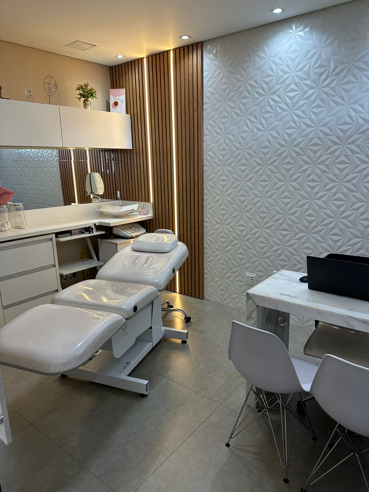 Sala de procedimentos faciais com parede 3D e maca